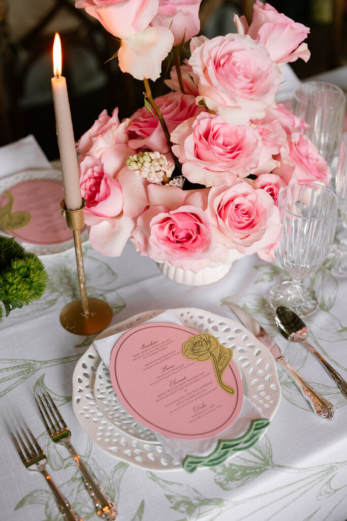 Lush blush pink rose centerpiece next to clear Park Lane glassware and Silver King Arthur flatware on a wedding table.