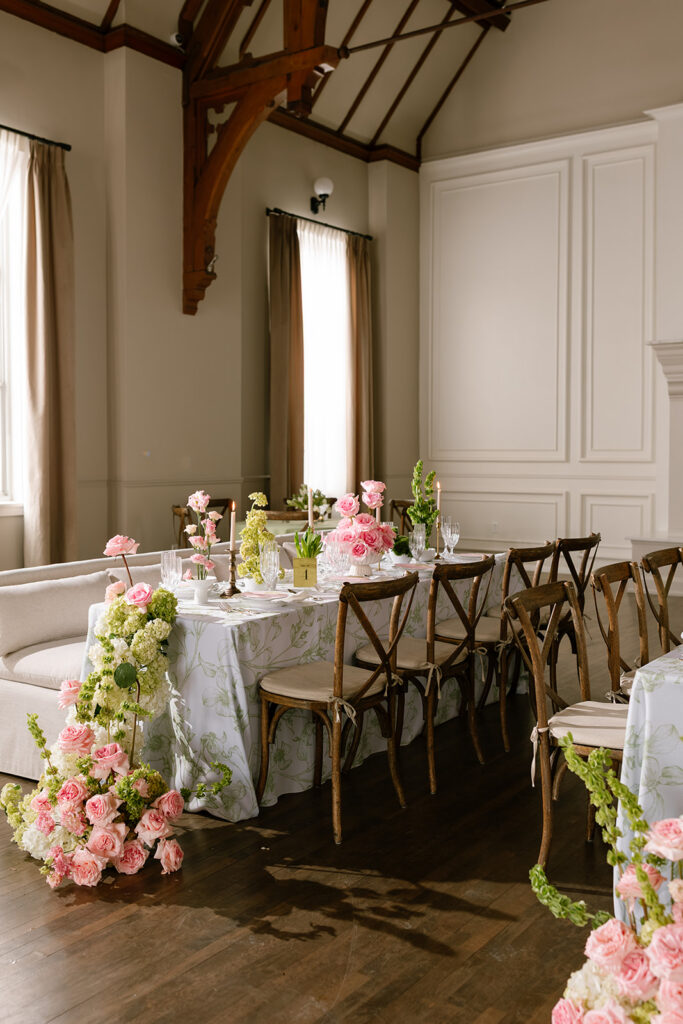 A spectacular cascading hydrangea and rose floral runner spilling over the edge of a botanical-print draped table.