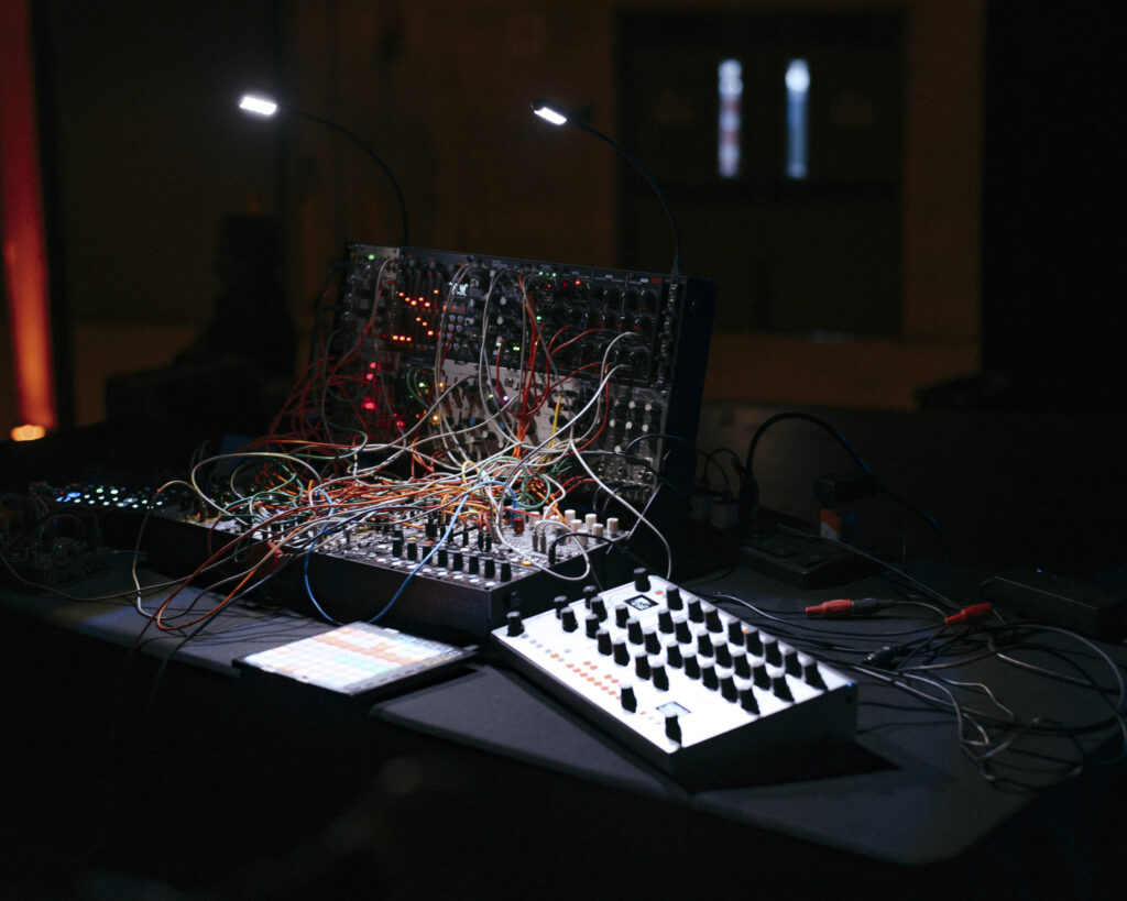 Electronic modular synthesizer setup providing live electronic soundscapes at a modern dinner party.
