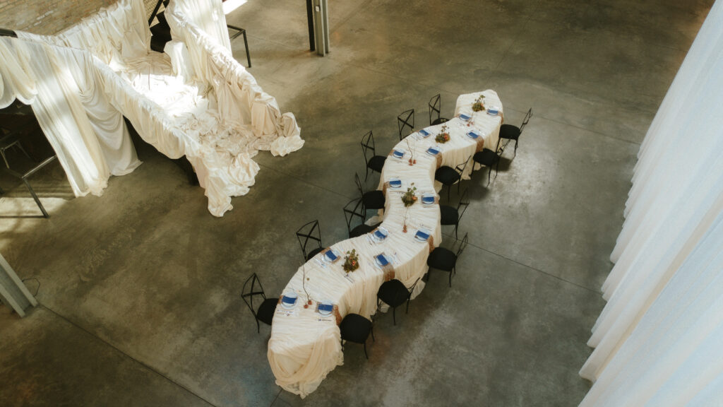 Overhead bird's-eye view of a winding serpentine table layout with black chameleon chairs at Fairlie Chicago by Tablescapes Event Rentals.