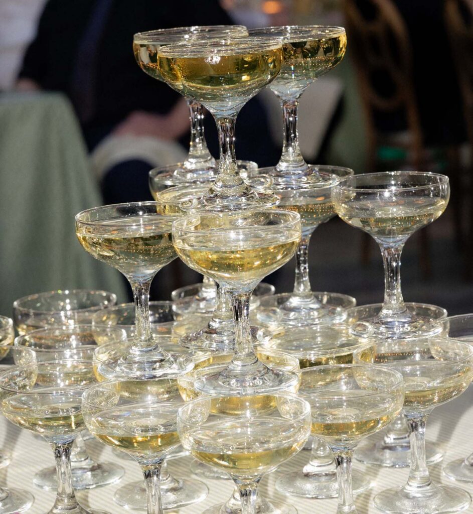 Close-up details of stacked champagne coupe glasses for a champagne tower setup by Tablescapes.