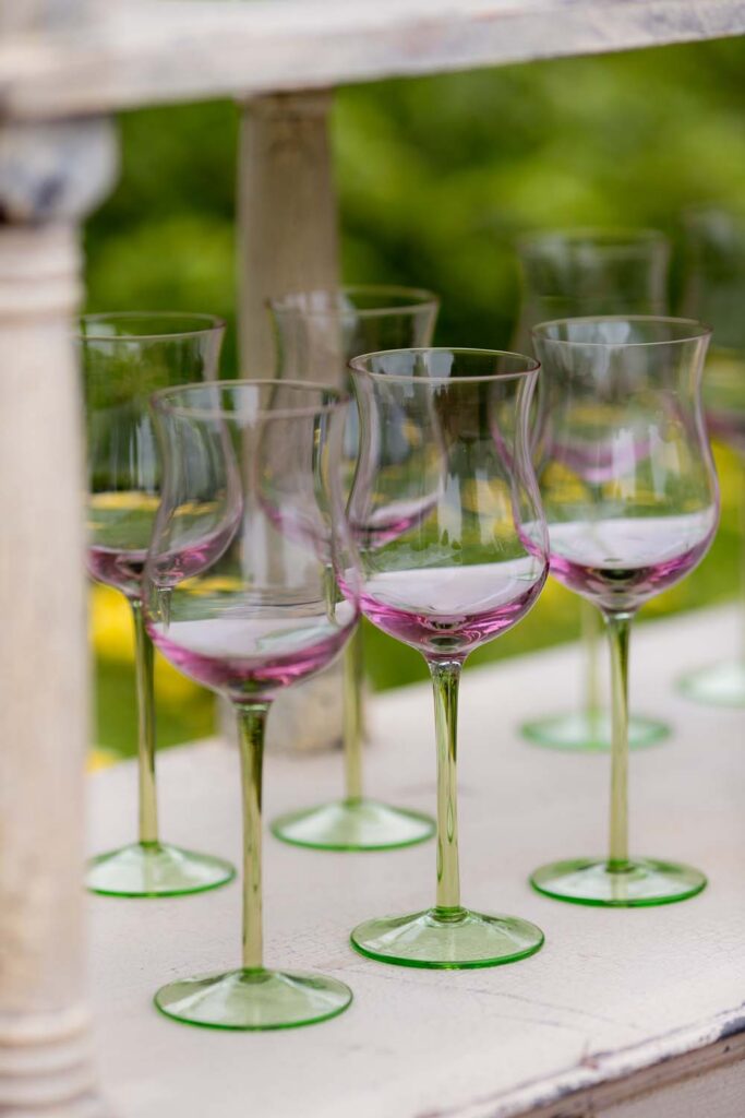 Elegant pink and green tulip glassware displayed on a rustic white shelf.